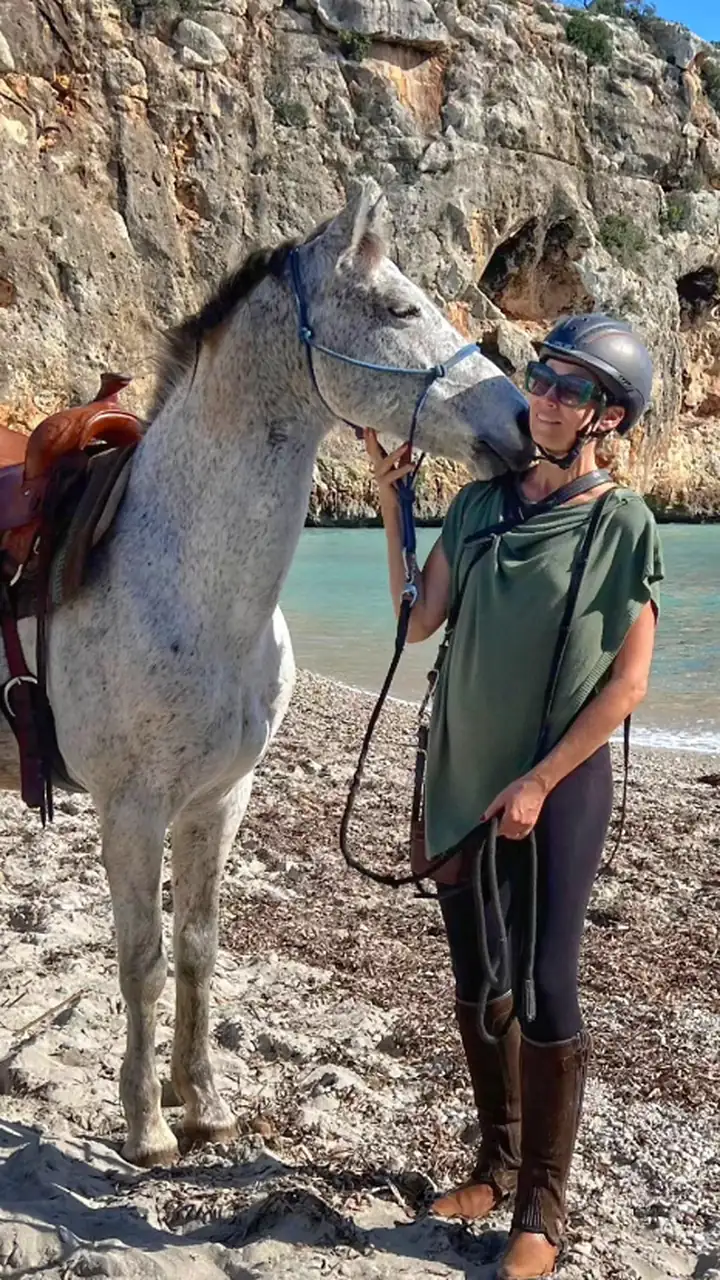 Rayne with a grey horse on the beach at a cala