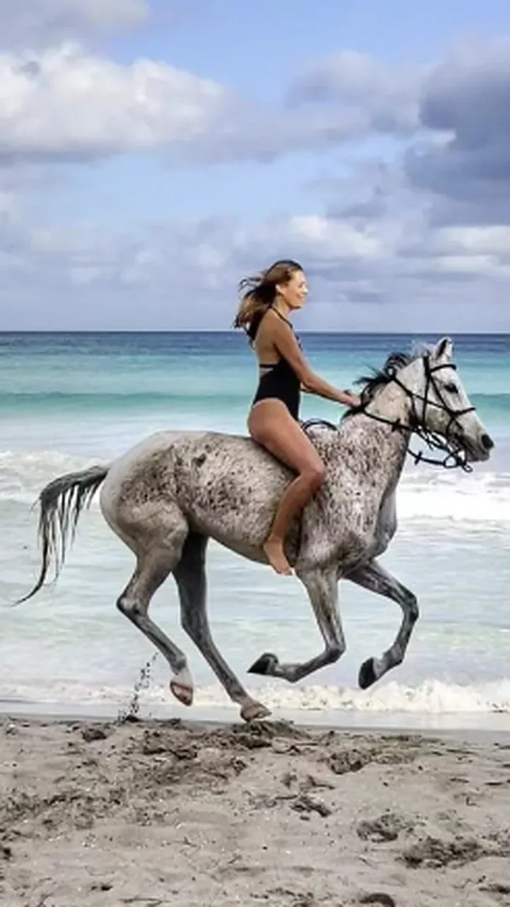 Rayne galloping a grey horse along the shoreline